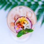 A photo of Snake Oil Cocktail Co's Batida cocktail from above. The cocktail is garnished with passionfruit and edible flowers
