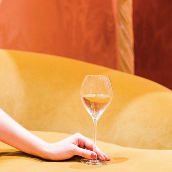 A woman holding a glass filled with champagne on a yellow couch